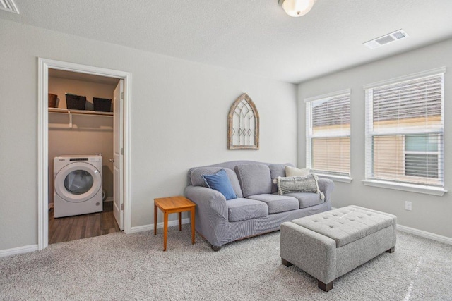 carpeted living room with washer / clothes dryer, baseboards, visible vents, and a textured ceiling