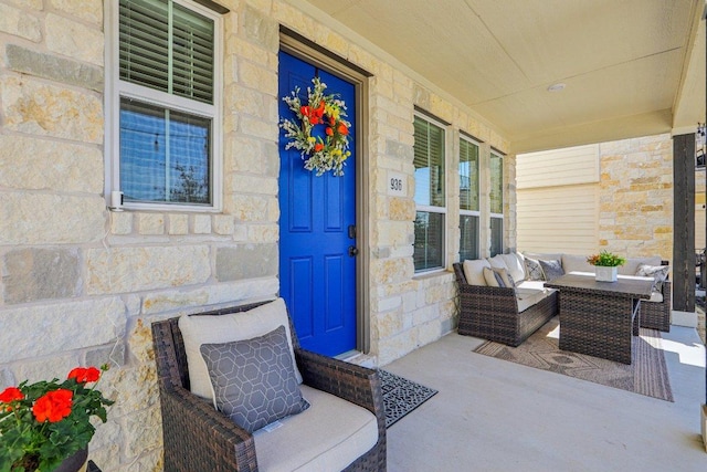 doorway to property with stone siding, covered porch, and an outdoor hangout area