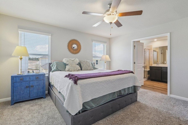 bedroom featuring ceiling fan, baseboards, light carpet, and ensuite bath