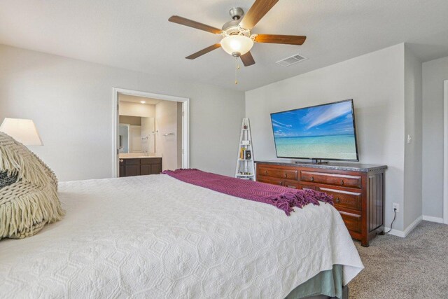 bedroom featuring visible vents, baseboards, light colored carpet, ensuite bathroom, and a ceiling fan