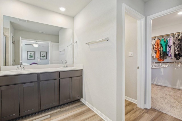 bathroom featuring a spacious closet, wood finished floors, visible vents, and a sink