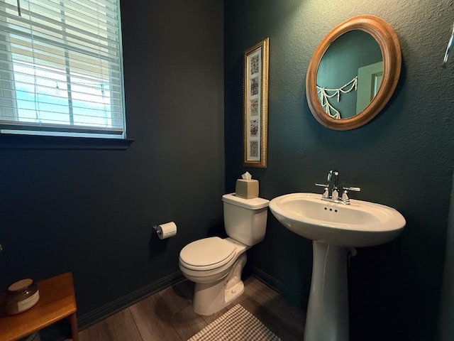 bathroom featuring toilet, wood finished floors, and baseboards