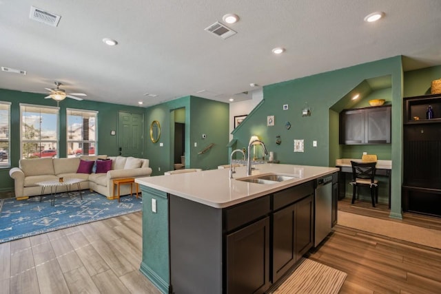 kitchen with visible vents, dishwasher, light countertops, an island with sink, and a sink