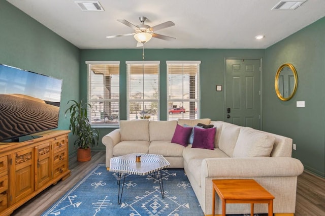 living room featuring baseboards, wood finished floors, visible vents, and ceiling fan