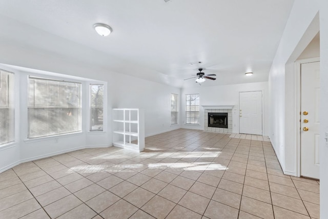 unfurnished living room with a ceiling fan, baseboards, light tile patterned flooring, and a tiled fireplace