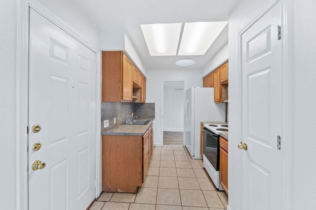 kitchen with white electric stove, light tile patterned flooring, a sink, baseboards, and backsplash