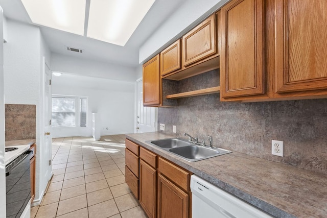 kitchen featuring light tile patterned floors, white appliances, a sink, visible vents, and decorative backsplash