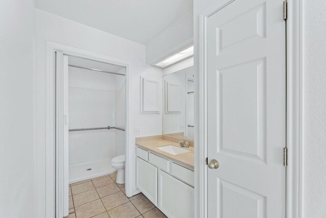 bathroom featuring toilet, a shower, tile patterned flooring, and vanity