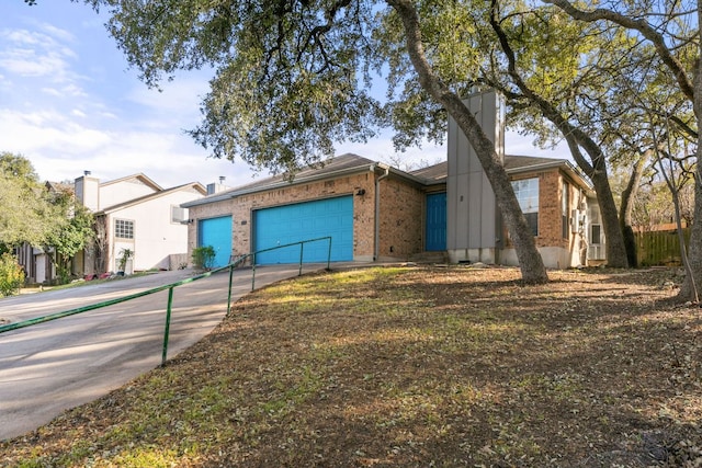 view of front facade with concrete driveway, brick siding, a chimney, and an attached garage