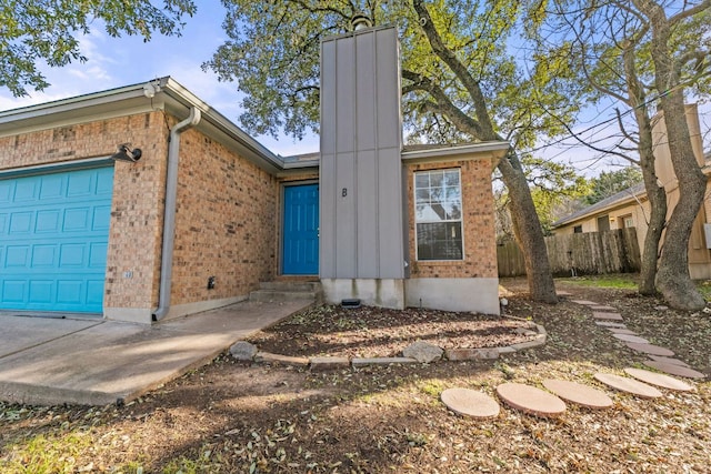 ranch-style home with a garage, a chimney, fence, and brick siding