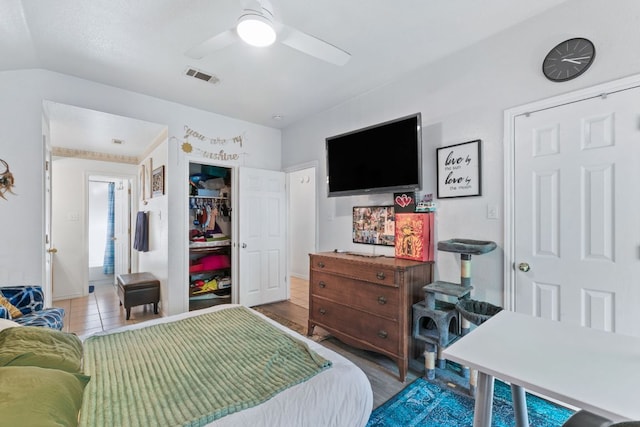 bedroom with lofted ceiling, wood finished floors, visible vents, a ceiling fan, and a closet