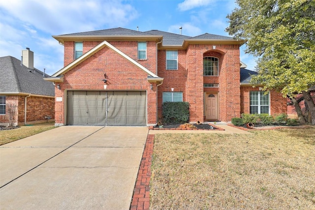 traditional-style home with a garage, a front yard, concrete driveway, and brick siding