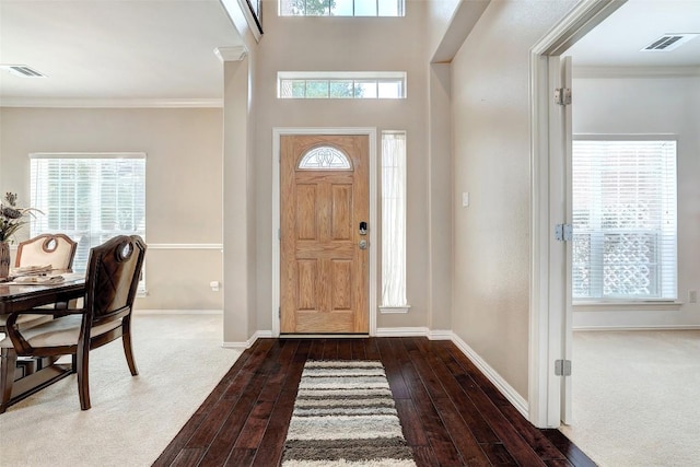 entrance foyer with ornamental molding, dark wood-style flooring, visible vents, and baseboards