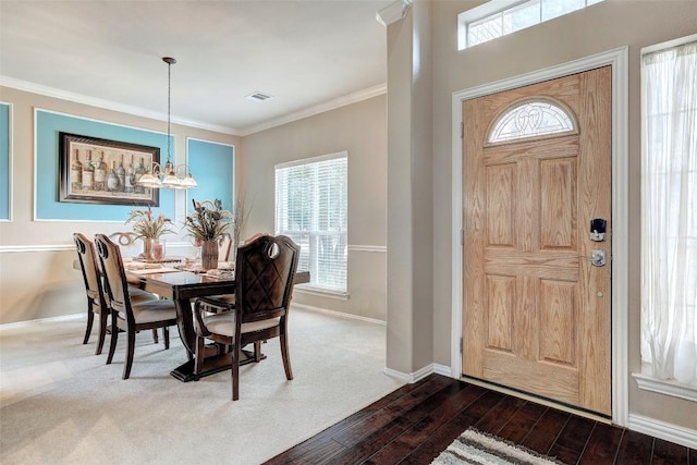 foyer entrance with baseboards, visible vents, dark wood-style floors, ornamental molding, and an inviting chandelier