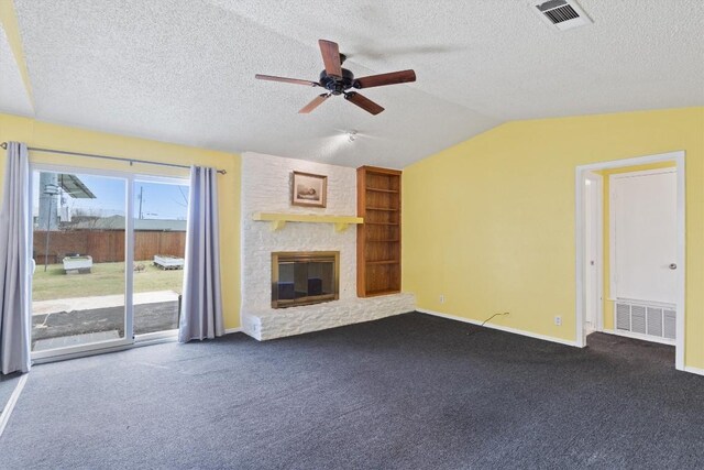 unfurnished living room with dark carpet, vaulted ceiling, visible vents, and a fireplace