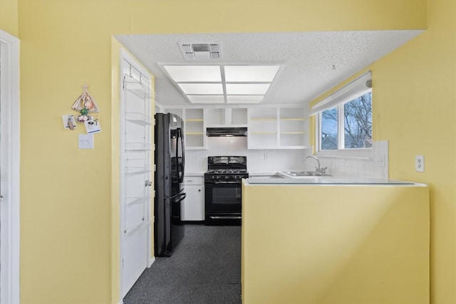 kitchen with a textured ceiling, under cabinet range hood, a sink, visible vents, and black appliances