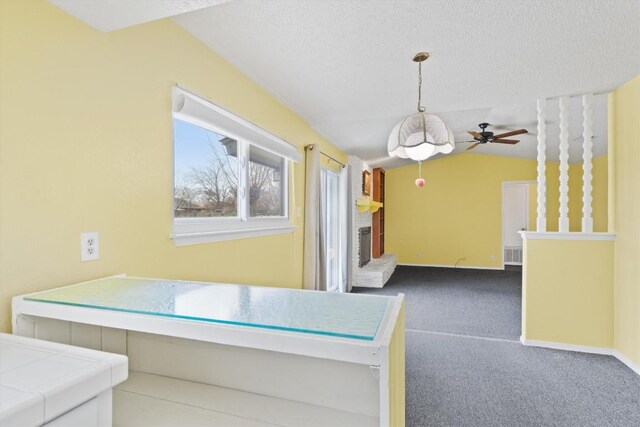 unfurnished dining area featuring visible vents, lofted ceiling, a textured ceiling, carpet flooring, and a brick fireplace