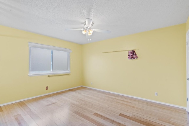 spare room with a textured ceiling, light wood finished floors, a ceiling fan, and baseboards