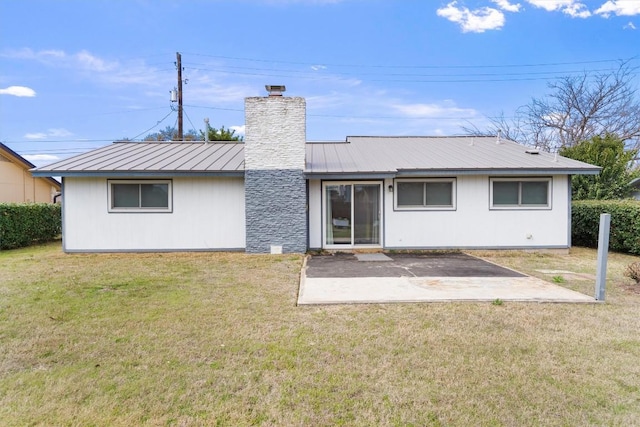 rear view of property with a yard, a patio, a chimney, a standing seam roof, and metal roof