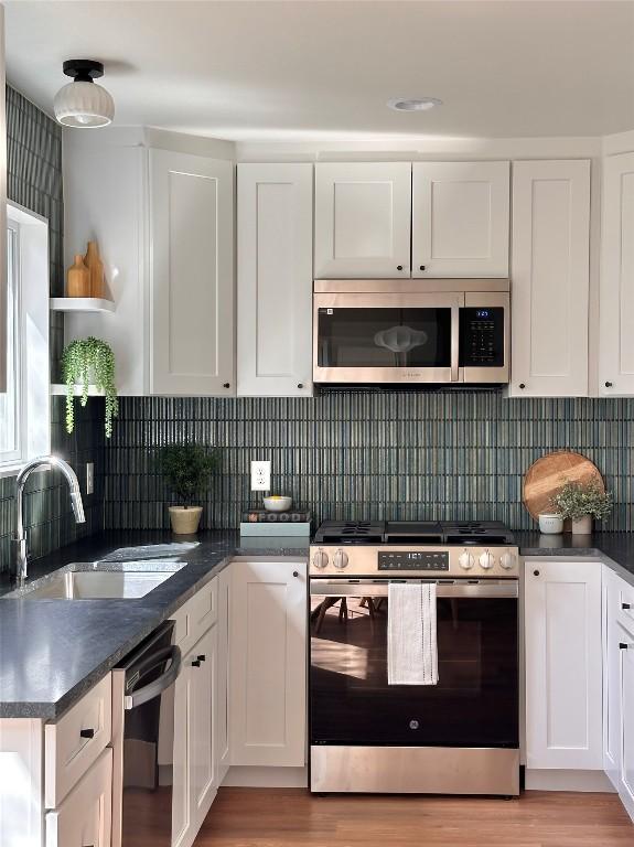 kitchen featuring a sink, dark countertops, white cabinetry, and stainless steel appliances