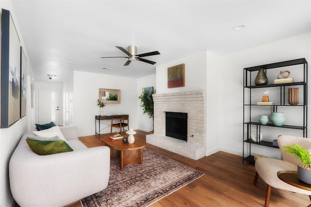 living area featuring wood finished floors, visible vents, baseboards, a fireplace, and ceiling fan