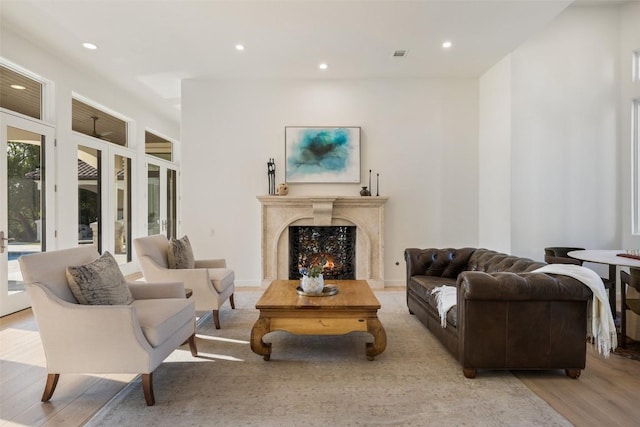 living area featuring a high end fireplace, visible vents, light wood-type flooring, and recessed lighting
