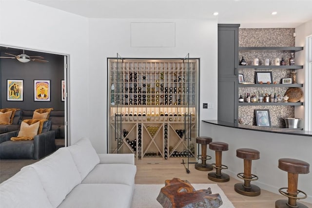 wine area with a bar, wood finished floors, and recessed lighting