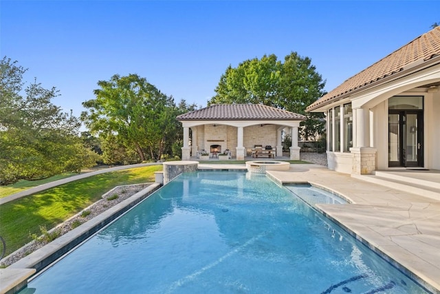 view of swimming pool featuring a gazebo, an outdoor fireplace, a yard, a pool with connected hot tub, and a patio