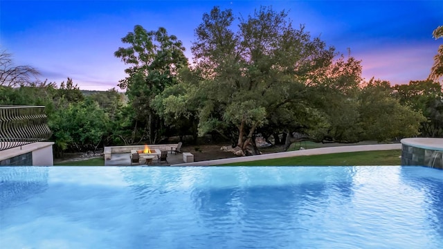 view of pool with an infinity pool, an outdoor fire pit, and a patio area