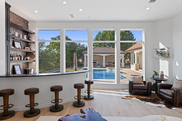 interior space featuring recessed lighting, wood finished floors, a wealth of natural light, and bar