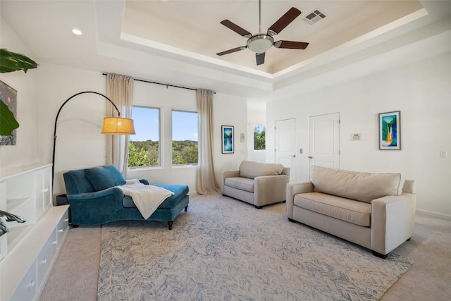 sitting room with carpet flooring, a raised ceiling, and visible vents