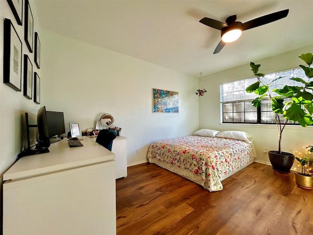 bedroom with ceiling fan, wood finished floors, and baseboards