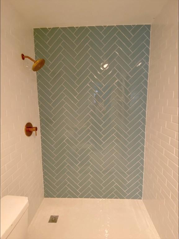 bathroom featuring tiled shower and toilet