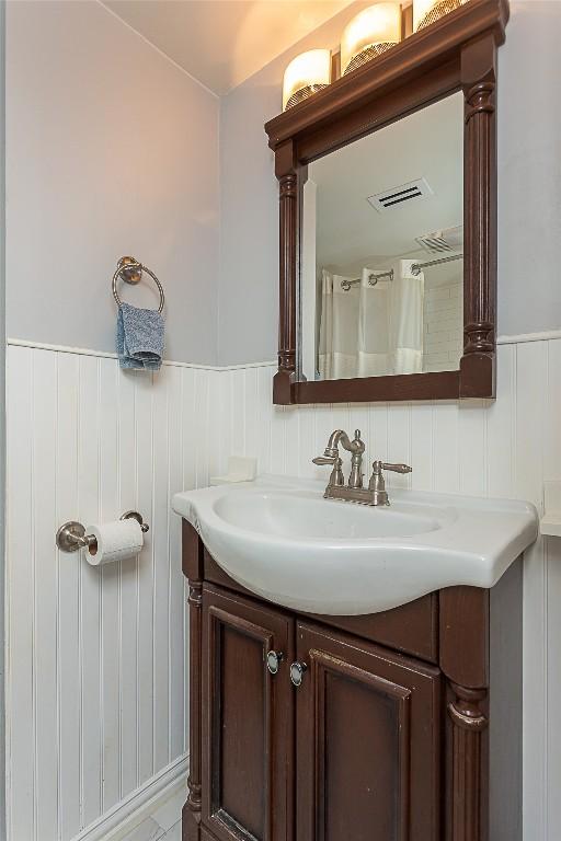 full bathroom with vanity, visible vents, and wainscoting