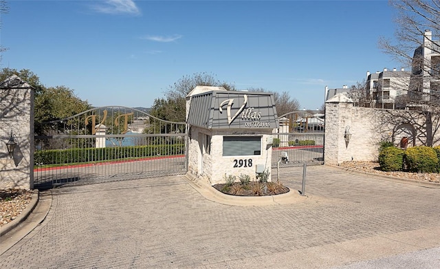 view of road with curbs, a gated entry, and a gate