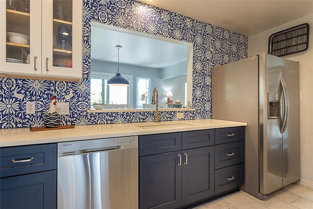 kitchen featuring a sink, backsplash, appliances with stainless steel finishes, light countertops, and glass insert cabinets