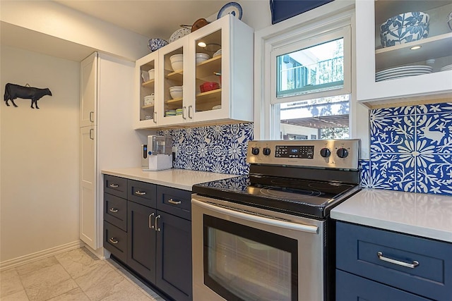 kitchen featuring marble finish floor, tasteful backsplash, stainless steel electric range, light countertops, and glass insert cabinets