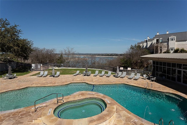 pool with a patio area, a community hot tub, and fence