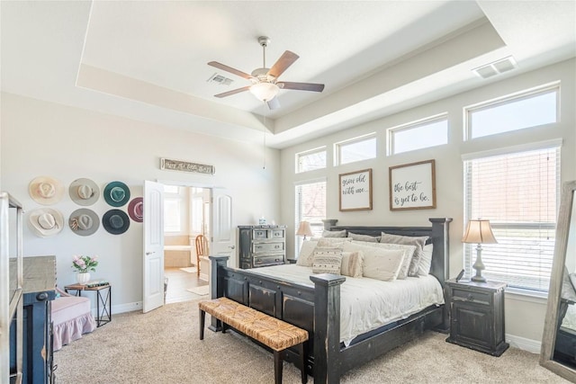 bedroom with a raised ceiling, visible vents, and light colored carpet