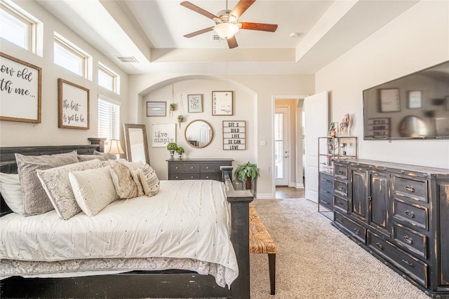 bedroom featuring baseboards, visible vents, ceiling fan, carpet, and a tray ceiling