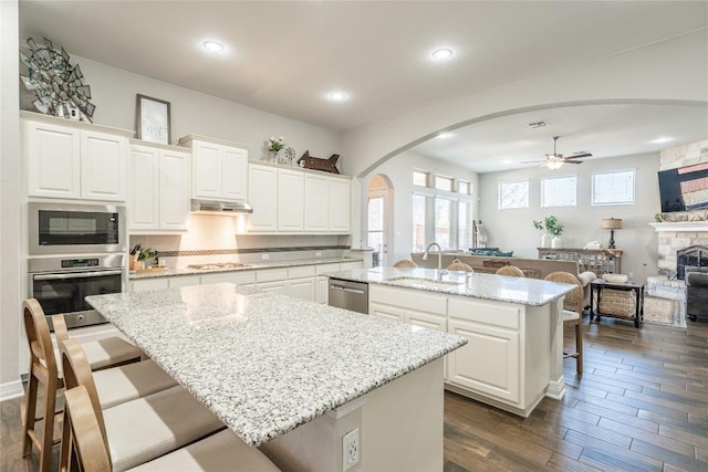 kitchen featuring a center island with sink, appliances with stainless steel finishes, a breakfast bar area, under cabinet range hood, and a sink