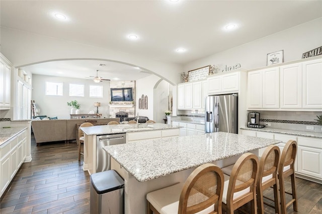 kitchen with stainless steel appliances, a ceiling fan, open floor plan, tasteful backsplash, and an island with sink