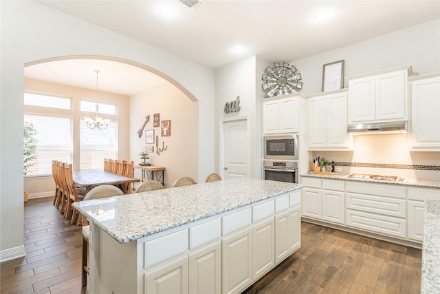 kitchen featuring gas cooktop, under cabinet range hood, dark wood-type flooring, stainless steel oven, and built in microwave