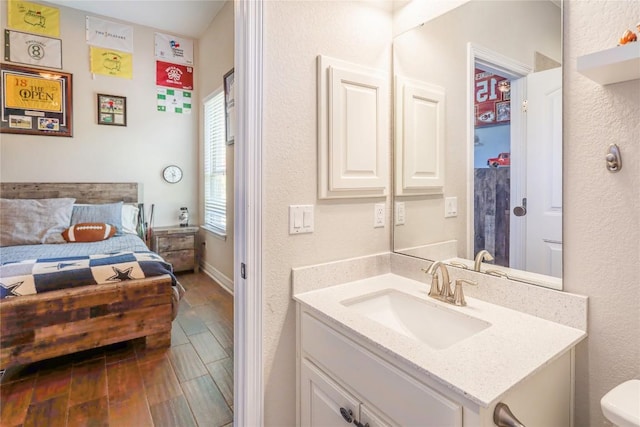 bathroom featuring wood finish floors, a textured wall, vanity, and toilet