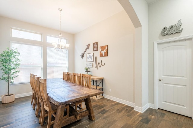 dining room with dark wood-type flooring, arched walkways, a chandelier, and baseboards