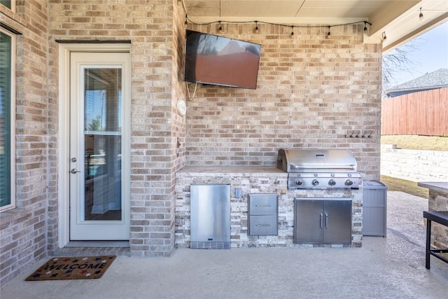 view of patio with a grill, fence, and exterior kitchen