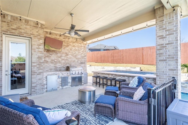 view of patio featuring ceiling fan, an outdoor hangout area, area for grilling, fence, and exterior kitchen