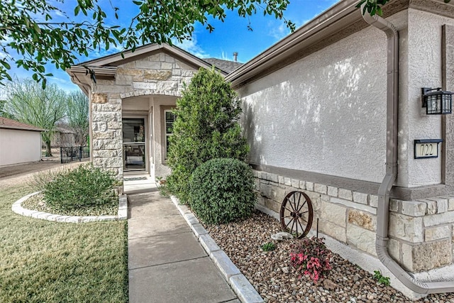 view of exterior entry featuring stone siding and stucco siding