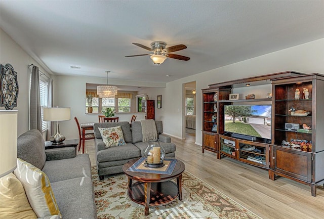 living area featuring baseboards, wood finished floors, visible vents, and a ceiling fan