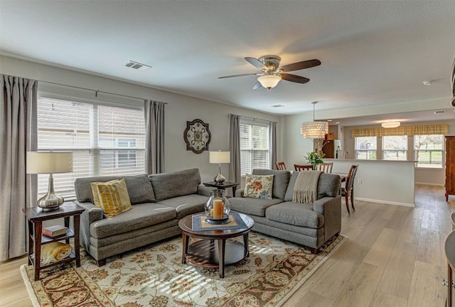 living room with visible vents, ceiling fan, and light wood finished floors